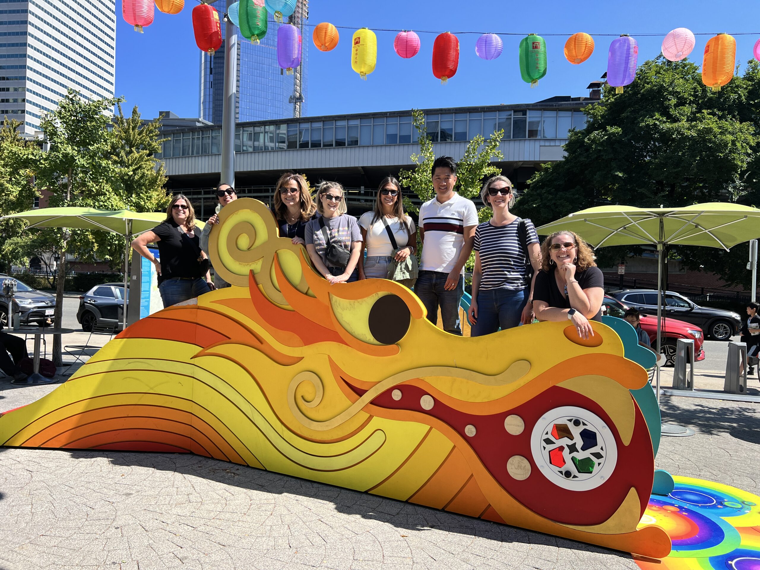 A group of people posing with an dragon cut out.