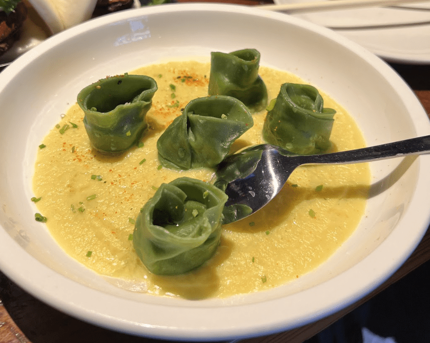 a bowl with yellow soup and green topping