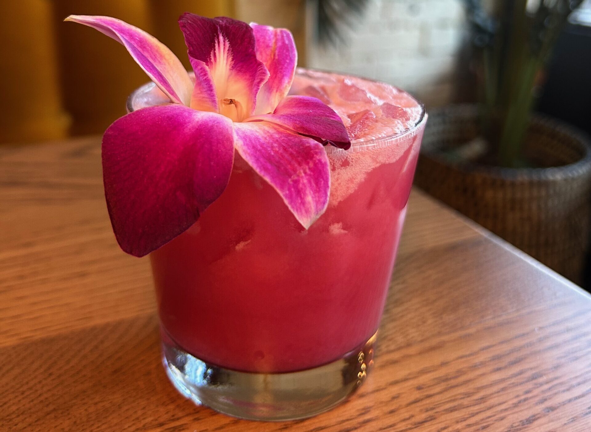 a pink cocktail on a table with a flower