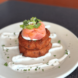 fried stacks of disc shaped food with salmon on top